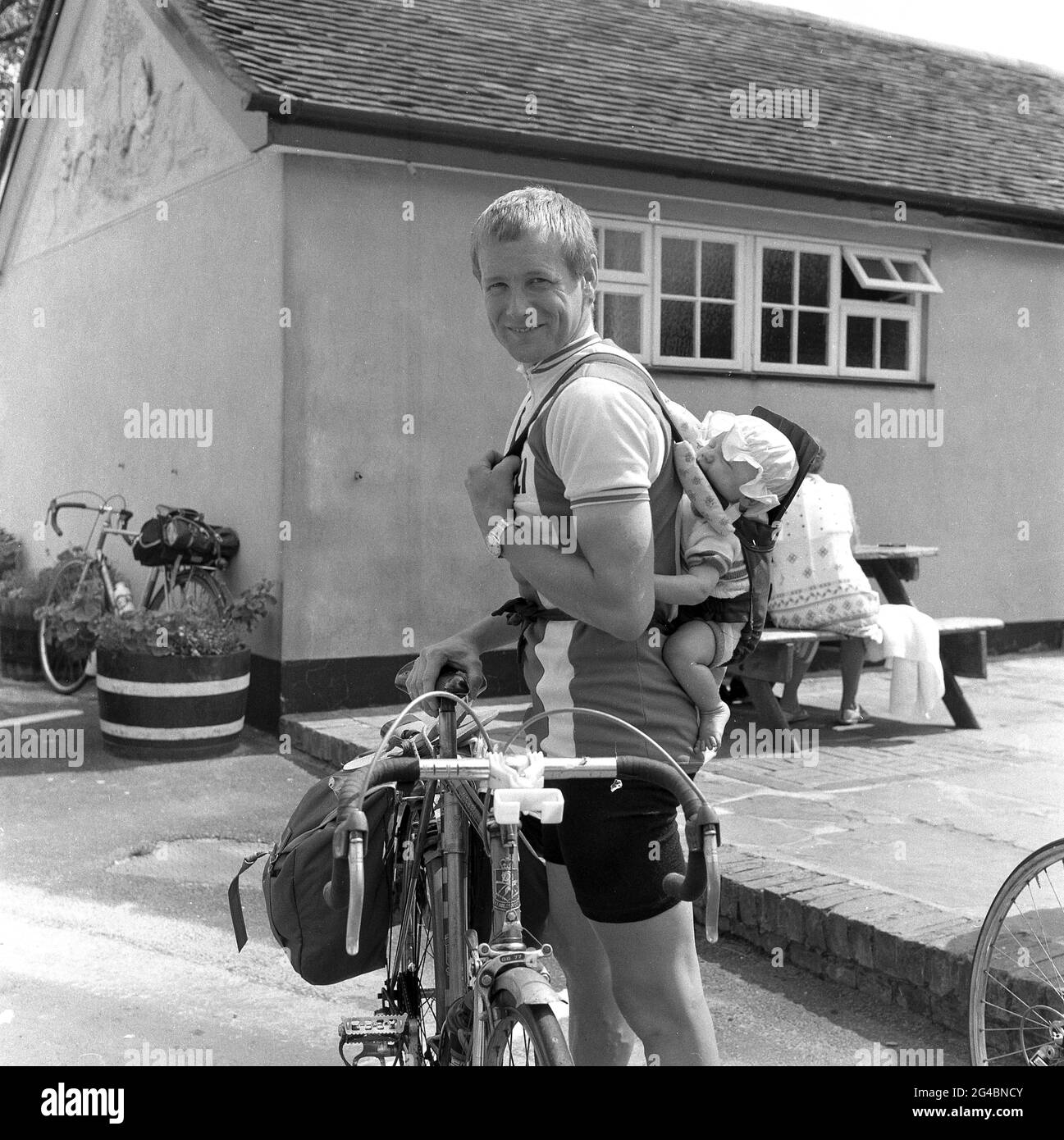 1980s, historical, male touring cyclist with an unusual backpack, his small infant child or toddler, Sussex, England, UK. Stock Photo