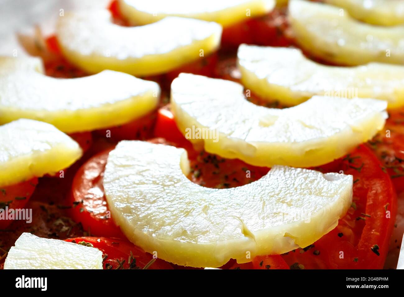 The combination of vegetables and fruits in the food. Cooking pineapples with tomatoes. A recipe for a delicious dish for quick cooking at home. Pineapple slices with tomatoes are ready for baking. Top view Stock Photo