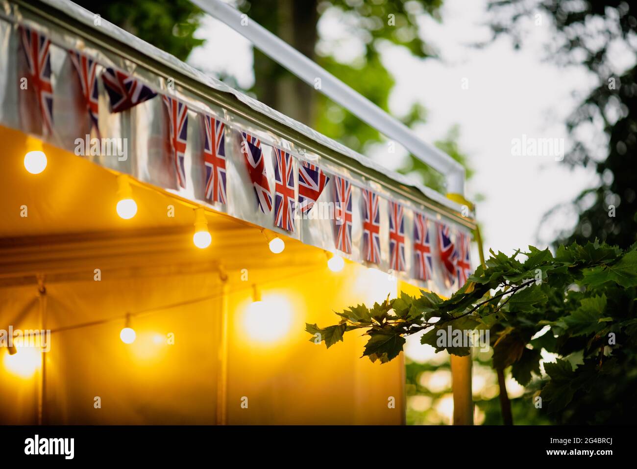 Shallow depth of field (selective focus) details with the British flag and a merchandise tent during a British themed garden party. Stock Photo