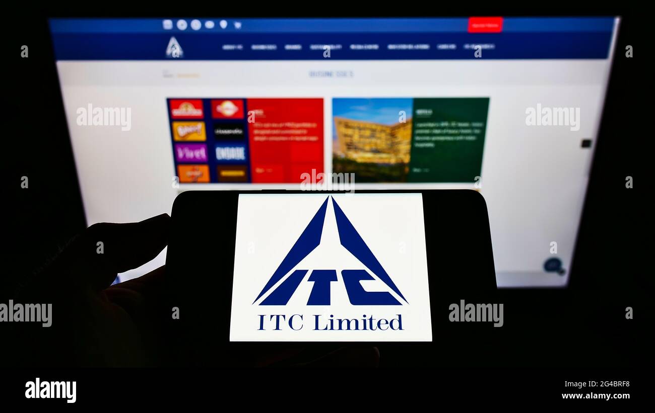 Person holding cellphone with logo of Indian conglomerate ITC Limited on screen in front of company webpage. Focus on phone display. Stock Photo