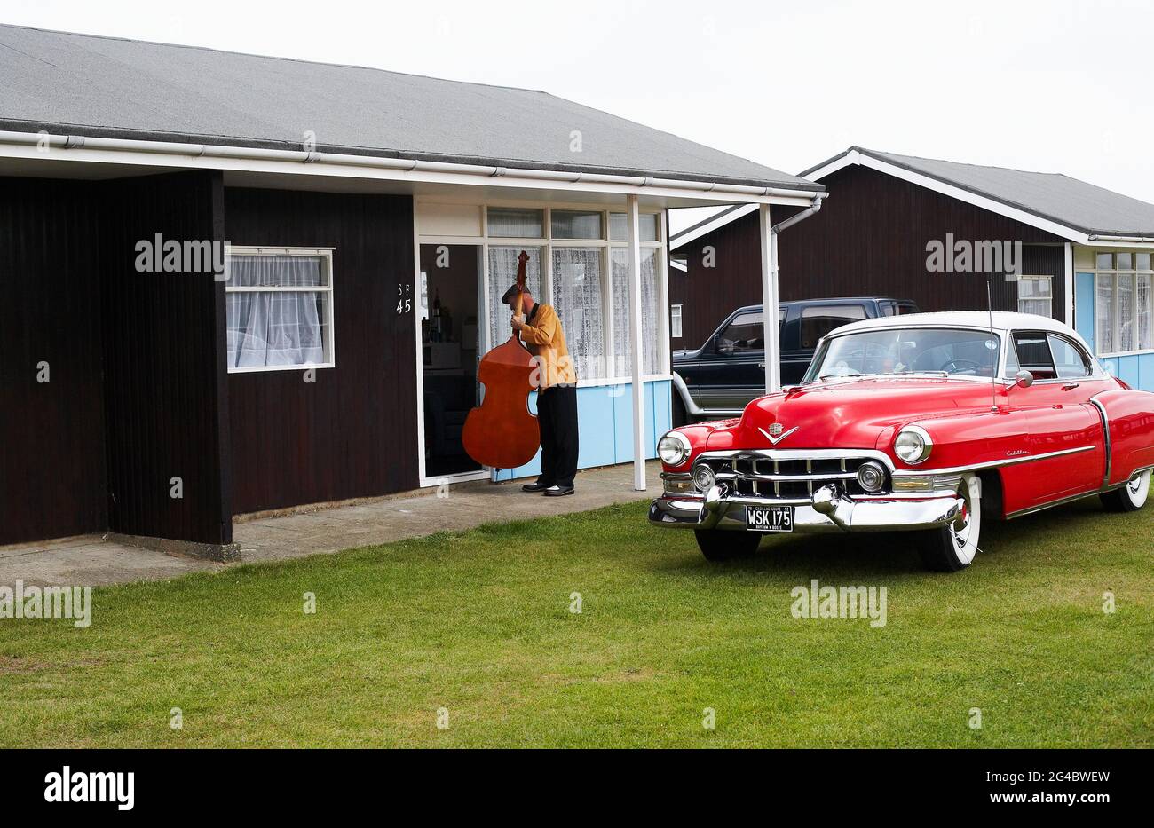 GREAT BRITAIN / England /Norfolk /Hemsby Rock 'N' Roll Weekender. A double bassist posing next to a red cadillac. Stock Photo