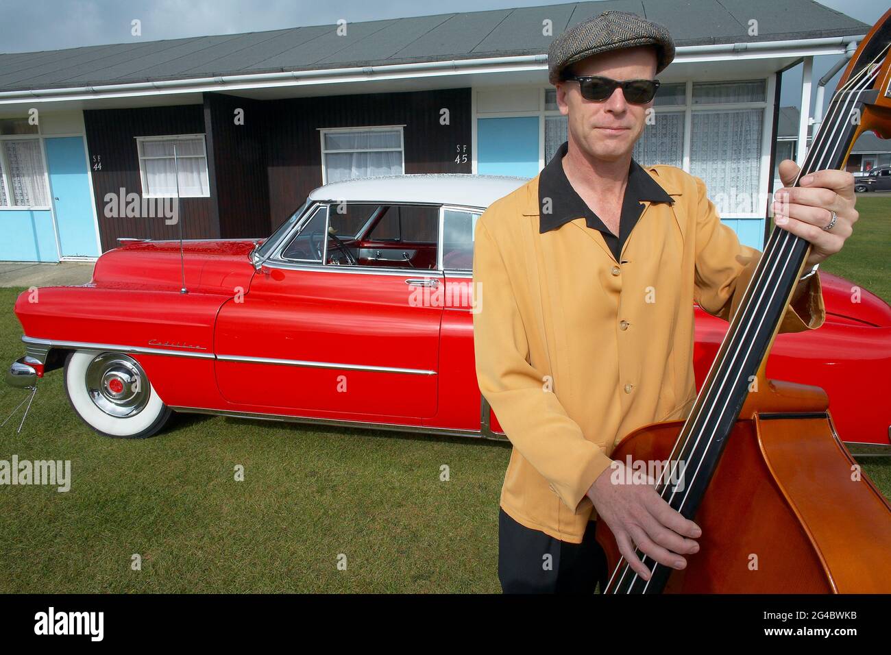 GREAT BRITAIN / England /Norfolk /Hemsby Rock 'N' Roll Weekender. A double bassist posing next to a red cadillac. Stock Photo