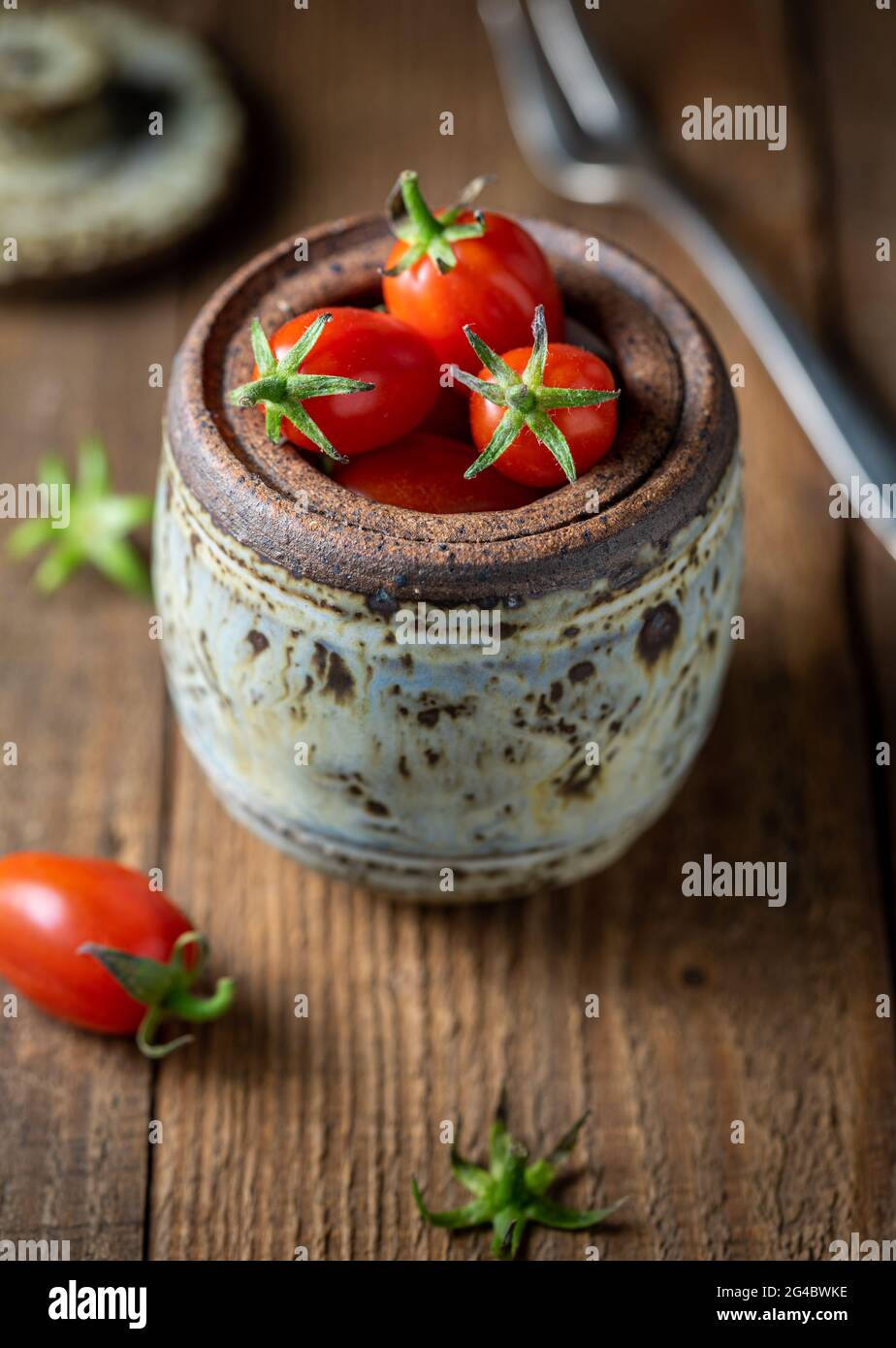 Grape tomatoes in clay jar. Stock Photo