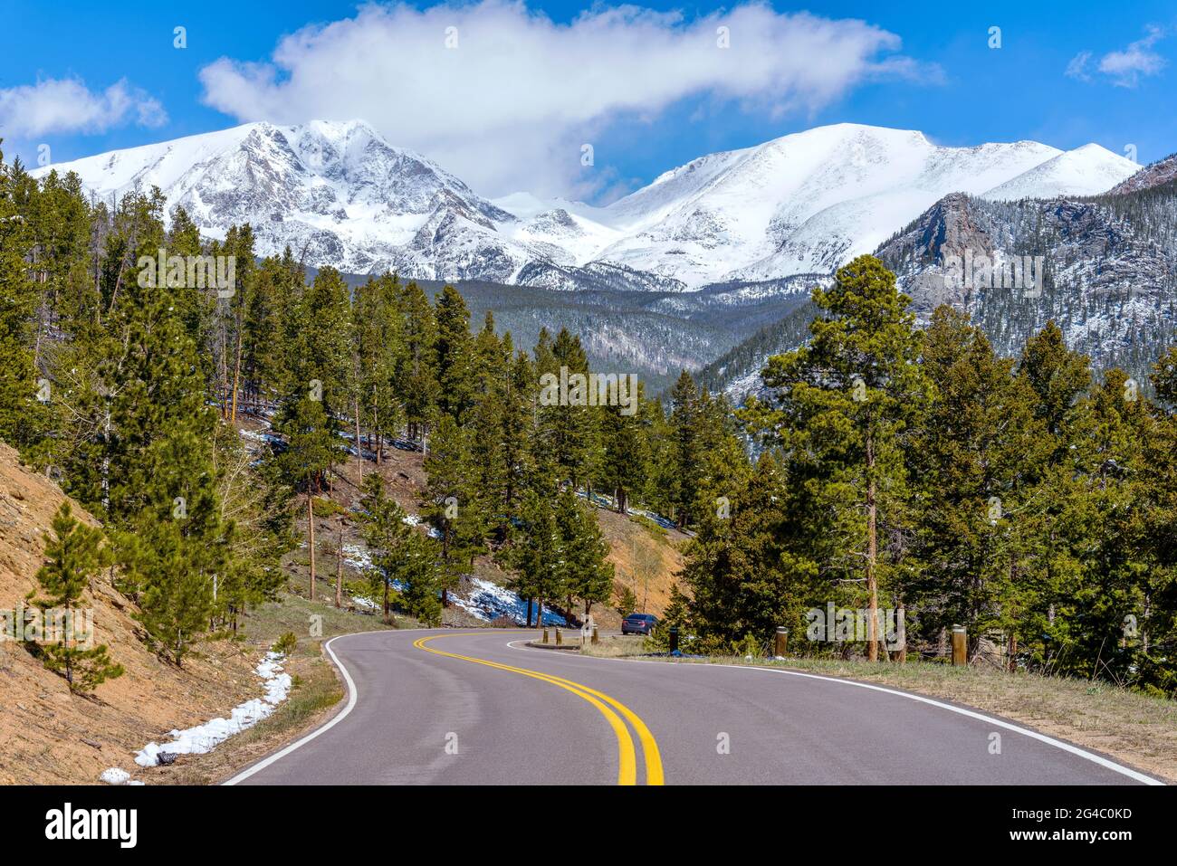 Spring Mountain Road - Spring view of winding Fall River Road, with snow-capped Mummy Range towering in background, Rocky Mountain National Park. Stock Photo