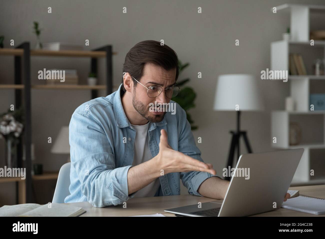 Angry confused young man looking at laptop screen. Stock Photo