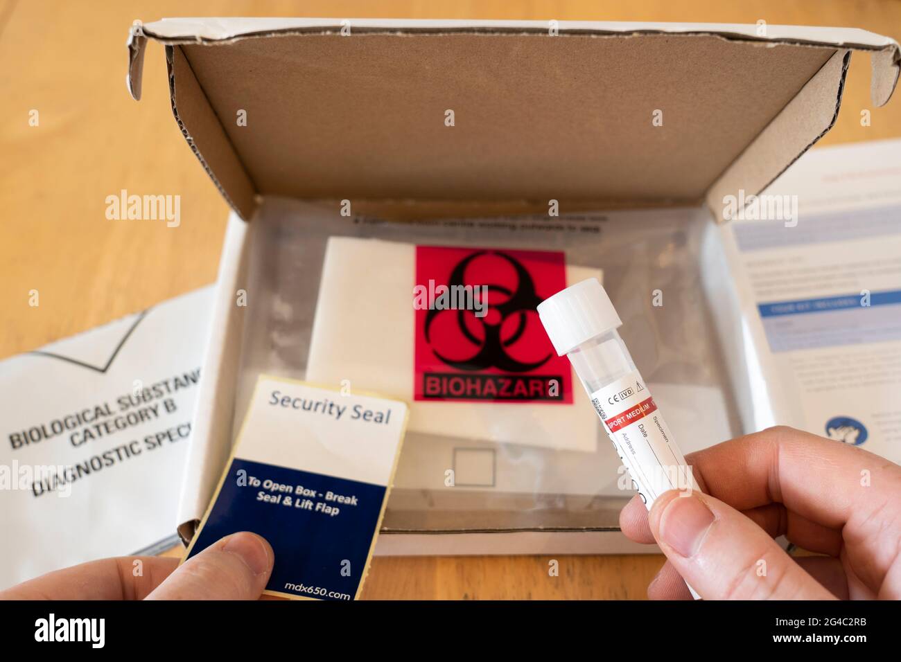 UK testing requirements require a Day 2 / 8 test during Covid-19. A man's hands holding a testing test tube with a testing box behind. June 2021 Stock Photo