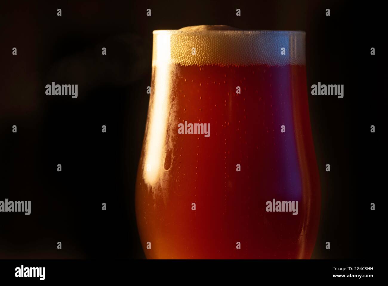 A glass of delicious craft beer served on an authentic beer glass, to be used as a background Stock Photo