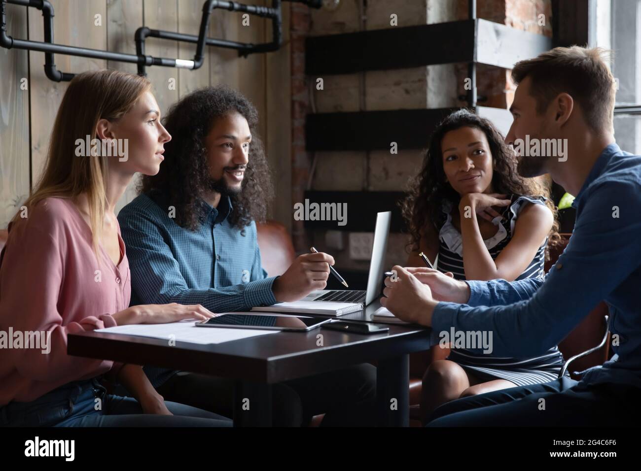 Motivated happy young mixed race employees working together in cafe. Stock Photo