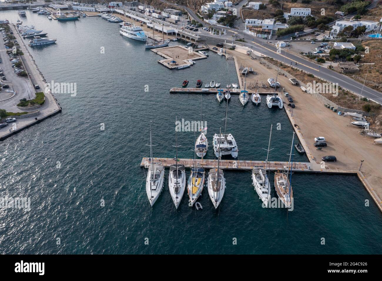 Greece, Cyclades. Mykonos island yacht marina aerial drone view. Mikonos small port, Sailing boats and motorboats anchored at harbour floating pier, C Stock Photo