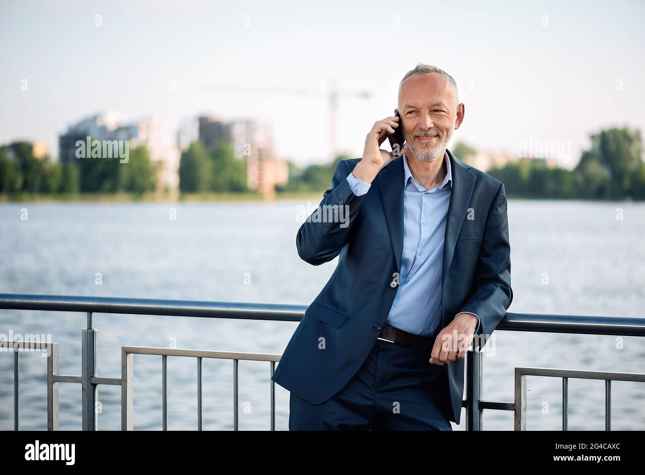 Smiling businessman in a gray suit with a smartphone Stock Photo - Alamy