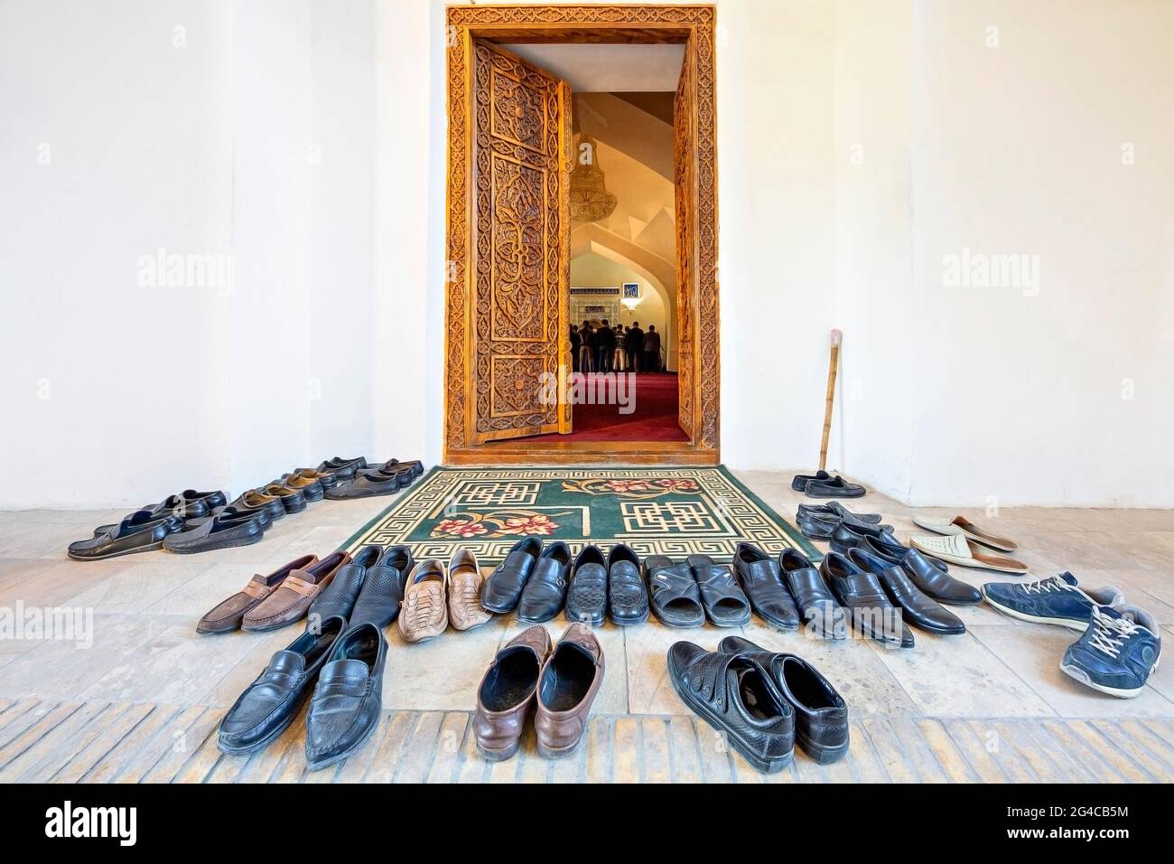 Shoes taken off to get in the mosque with people praying in the background, Samarkand, Uzbekistan Stock Photo