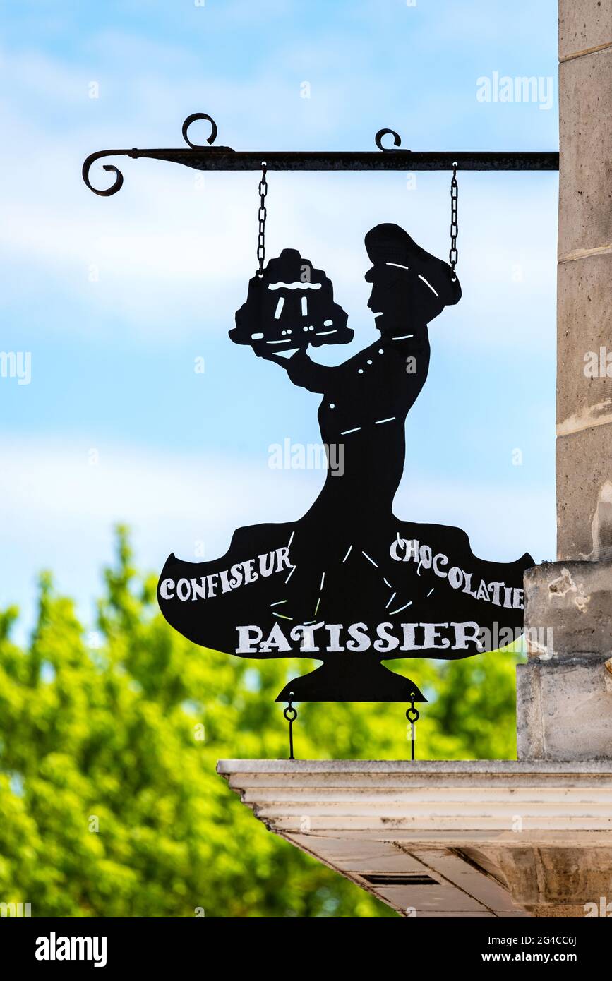 Vintage pastry shop sign depicting the silhouette of a pastry chef holding a cake with the words 'confectioner, chocolatier and pastry chef'. Stock Photo
