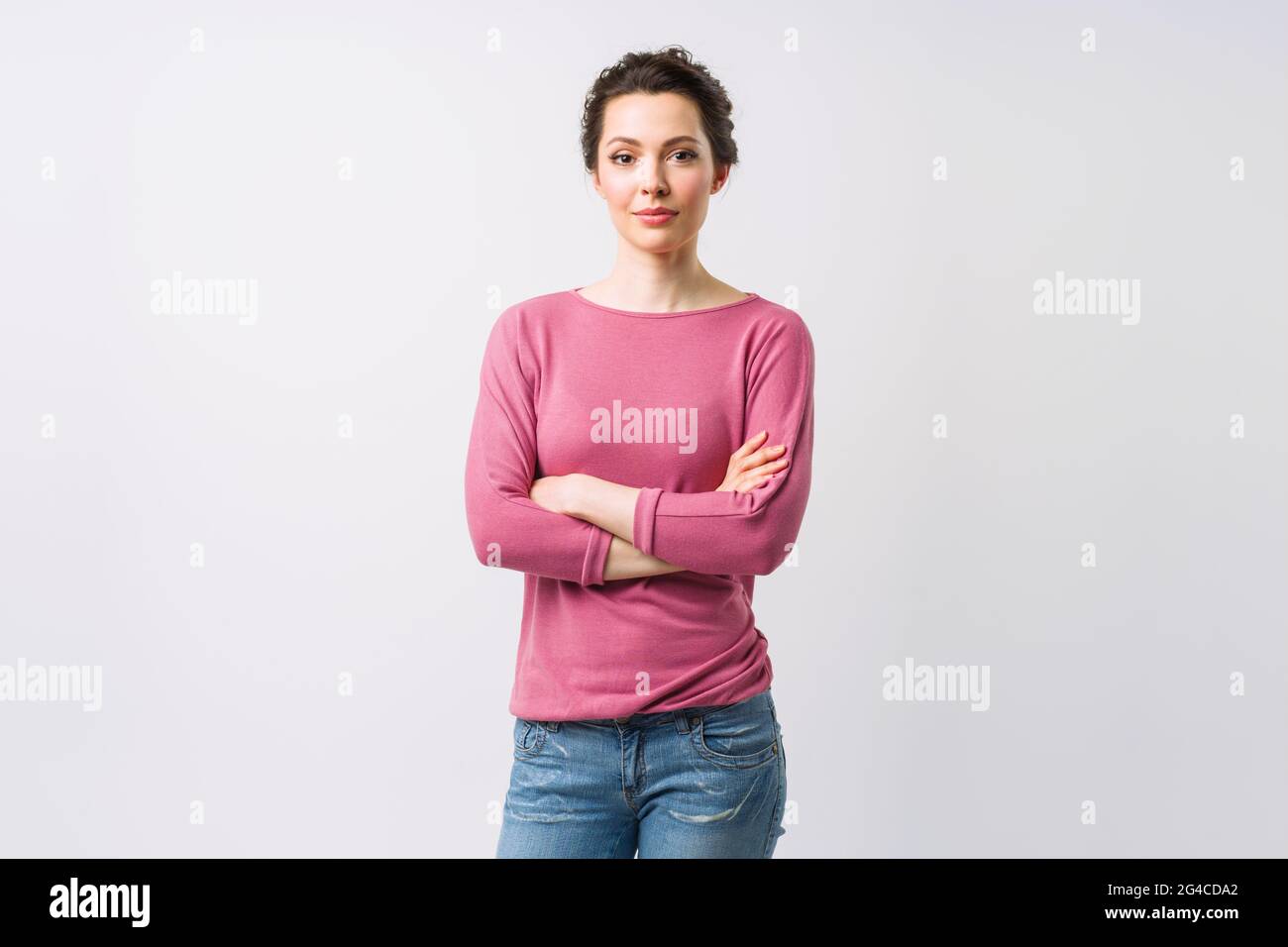 Young woman portrait. Adorable brunette in a sweater looking at the camera with her arms crossed. Stock Photo