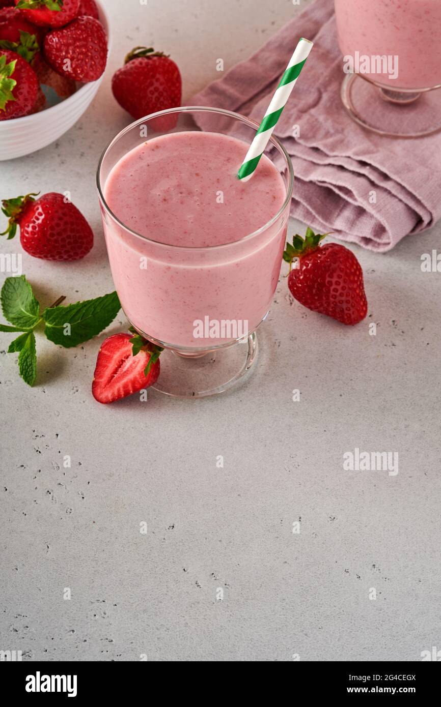 Strawberry smoothie or milkshake with berries and mint in tall glass on