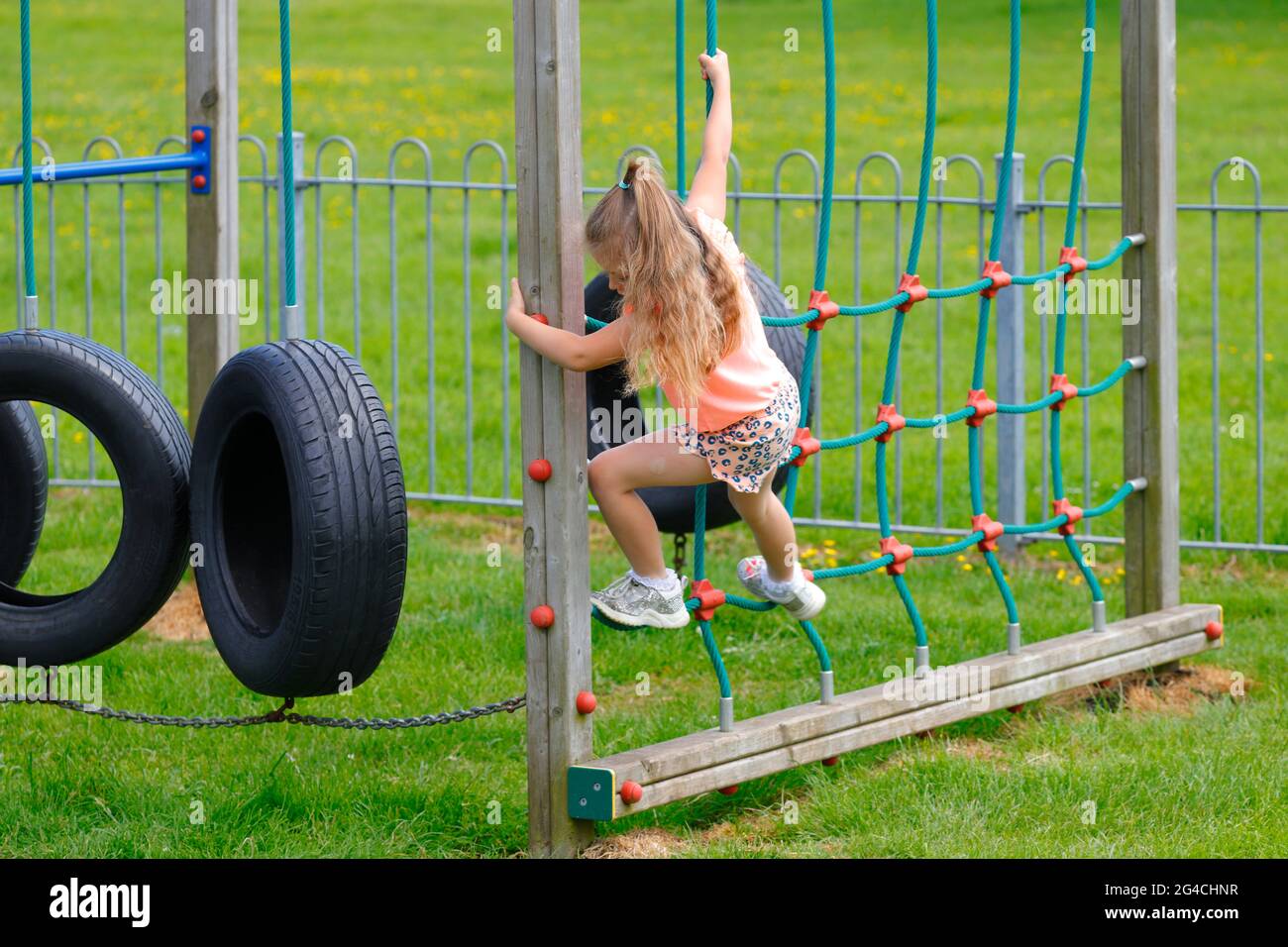 A 5 year old girl climbs across tyres on a play park in Flamborough,East Yorkshire,UK Stock Photo