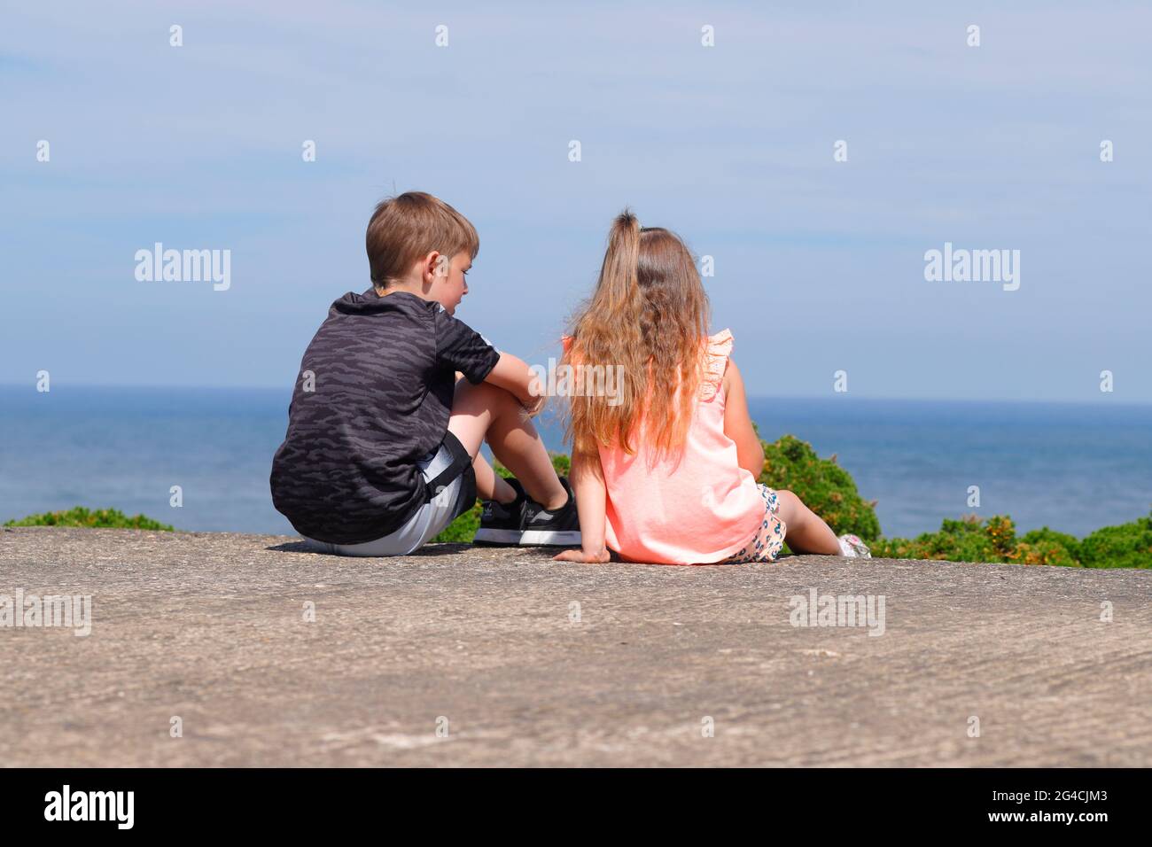 Brother and sister looking out to see from cliff tops at Flamborough Head in East Yorkshire,UK Stock Photo
