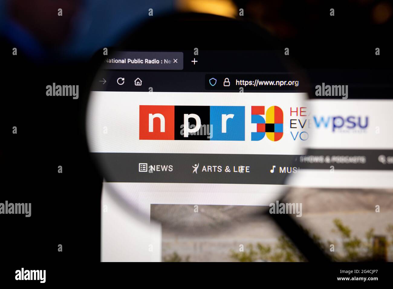 NPR company logo on a website, seen on a computer screen through a magnifying glass. Stock Photo