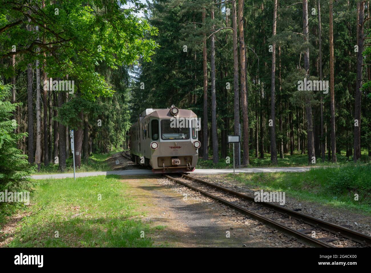 Narrow gauge (760 mm) train consisting of atypical modernized M27 (class 805.9) passenger unit on a railroad crossing near Dolní Radouň, Czechia. Stock Photo