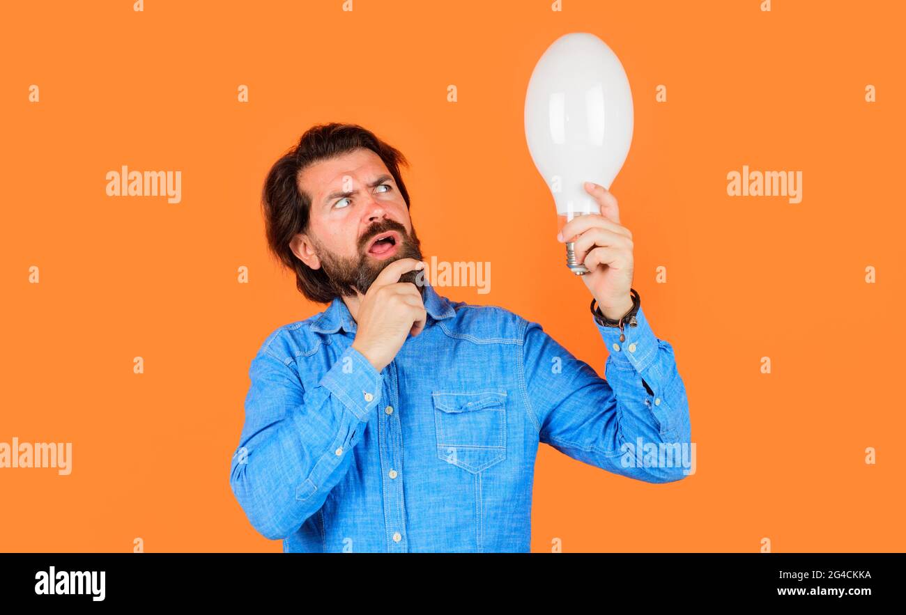 Pensive man with big lamp. Bearded thinking man with light bulb. New idea generator. Energy saving. Stock Photo