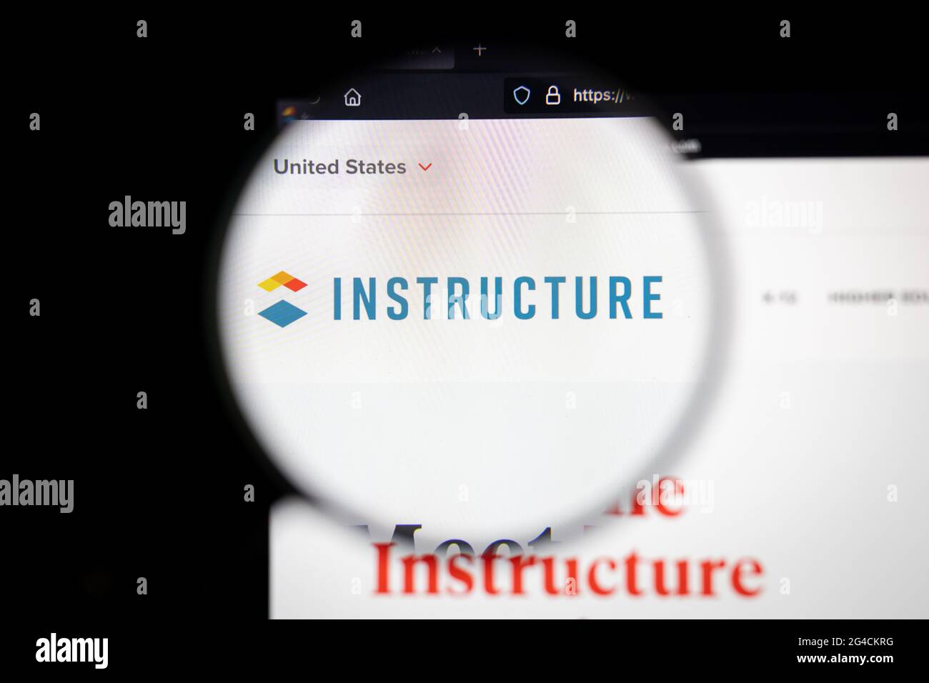 Instructure company logo on a website, seen on a computer screen through a magnifying glass. Stock Photo