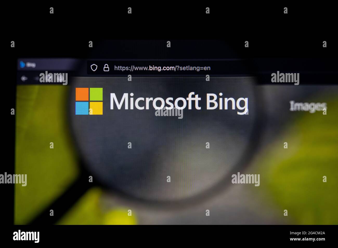 Bing search engine logo on a website, seen on a computer screen through a magnifying glass. Stock Photo