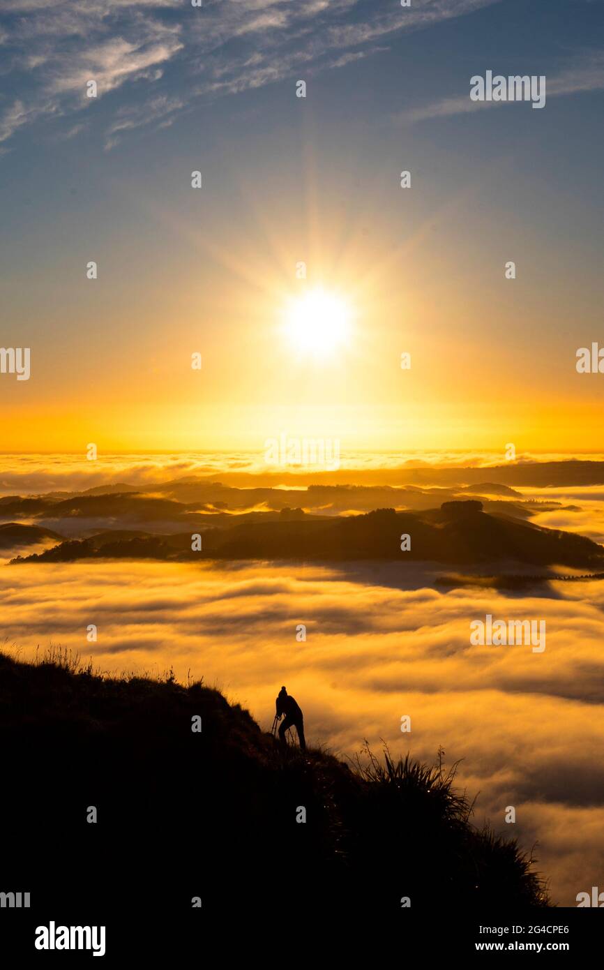 Landscape Photographer taking pictures of sunrise and morning fog atTe Mata Peak, Hawke's Bay, New Zealand Stock Photo
