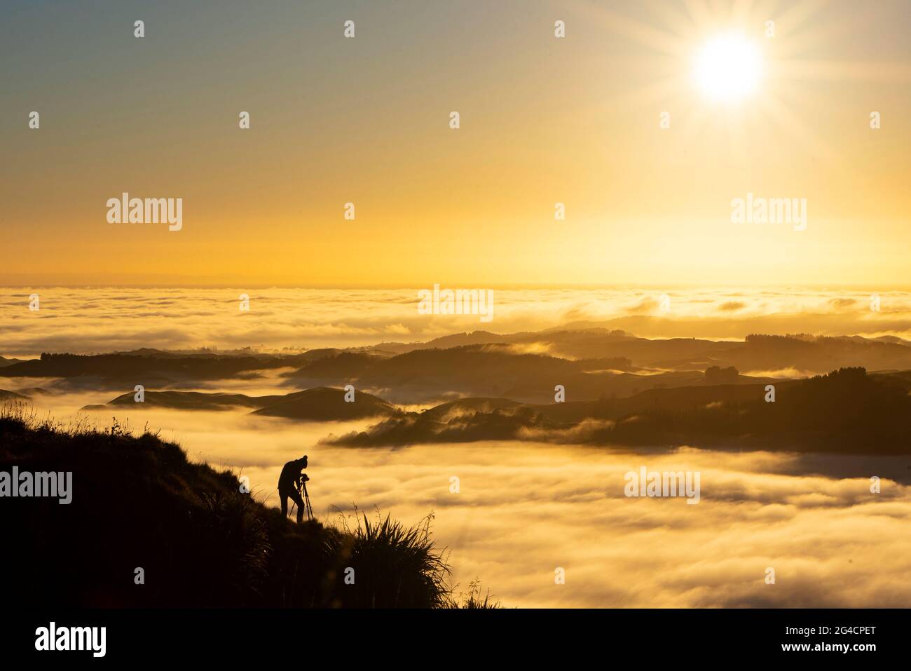 Landscape Photographer taking pictures of sunrise and morning fog atTe Mata Peak, Hawke's Bay, New Zealand Stock Photo