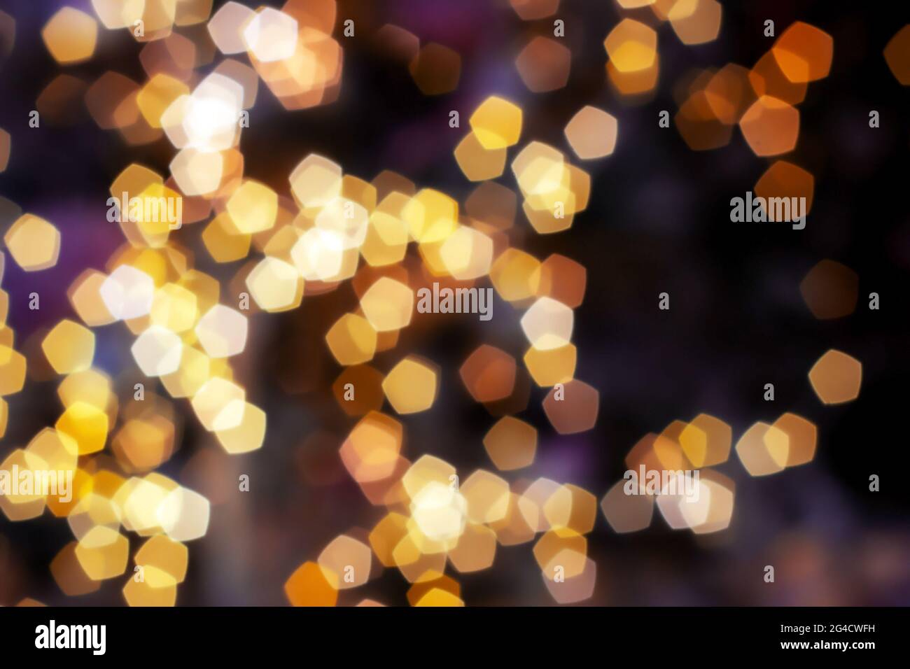 Blurred golden lights abstract background in the night, defocused dark glowing bokeh backdrop, magical yellow illuminated sparkle pattern. Stock Photo