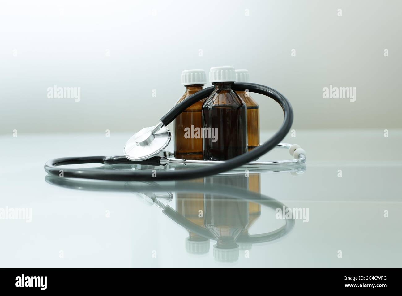 A stethoscope and three medicine bottles lie on a glass table Stock Photo