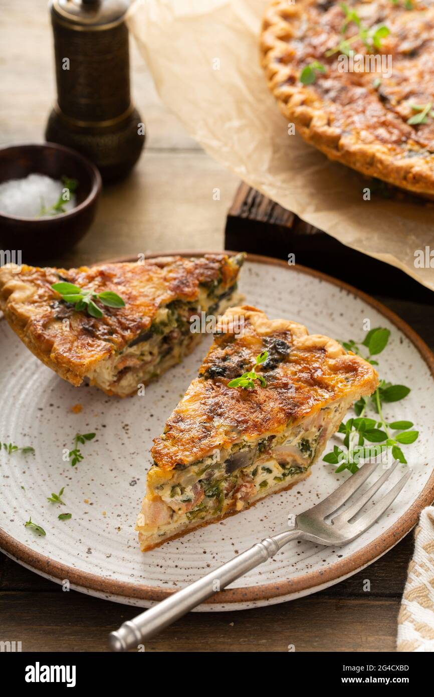 Bacon, mushroom and spinach quiche with cheese and herbs Stock Photo