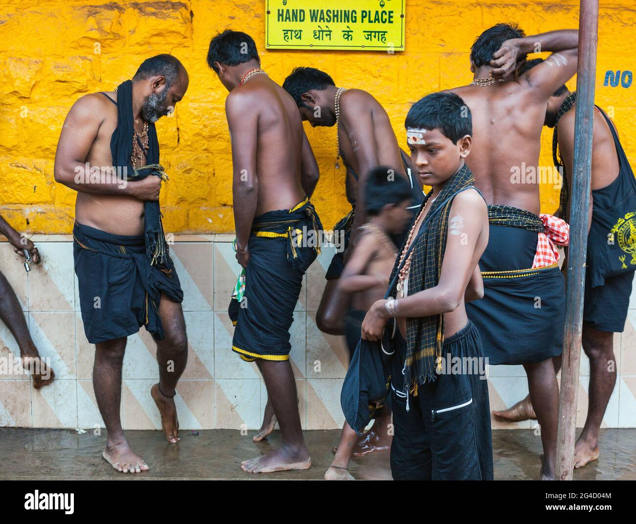 Ayappa devotees wearing black clothing washing feet outside Mahabaleshwar Temple, Gokarna, Karnataka, India Stock Photo