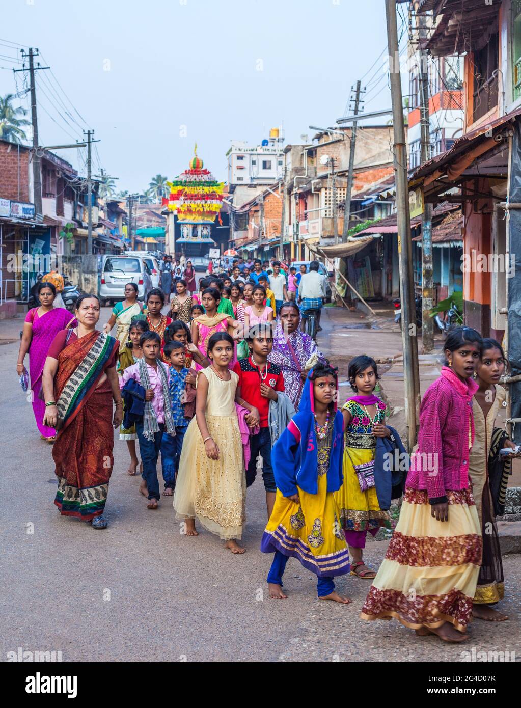 Young Indian schoolchildren wearing colourful clothes walk in large group through street, Gokarna, Karnataka, India Stock Photo