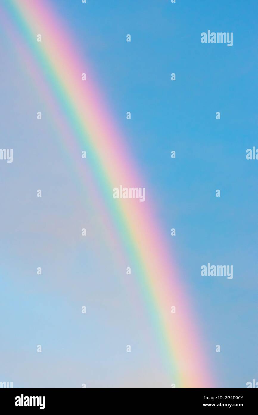 Rainbow in blue with clouds sky background with copy space during sunset Stock Photo