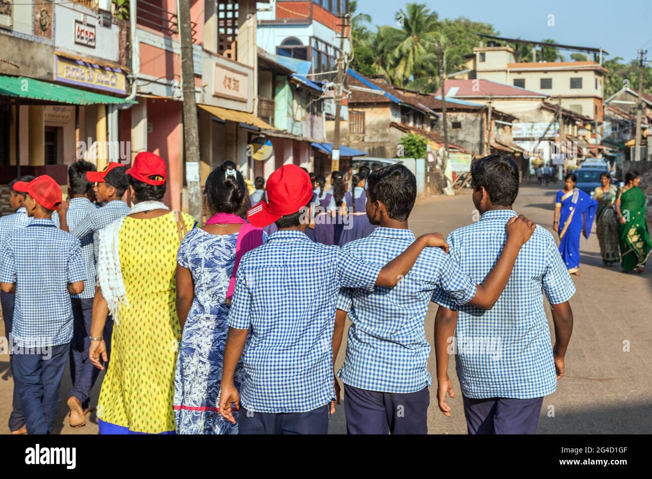 Rear view of three Indian schoolboys with arms on each other's shoulders walking down the street, Gokarna, Karnataka, India Stock Photo