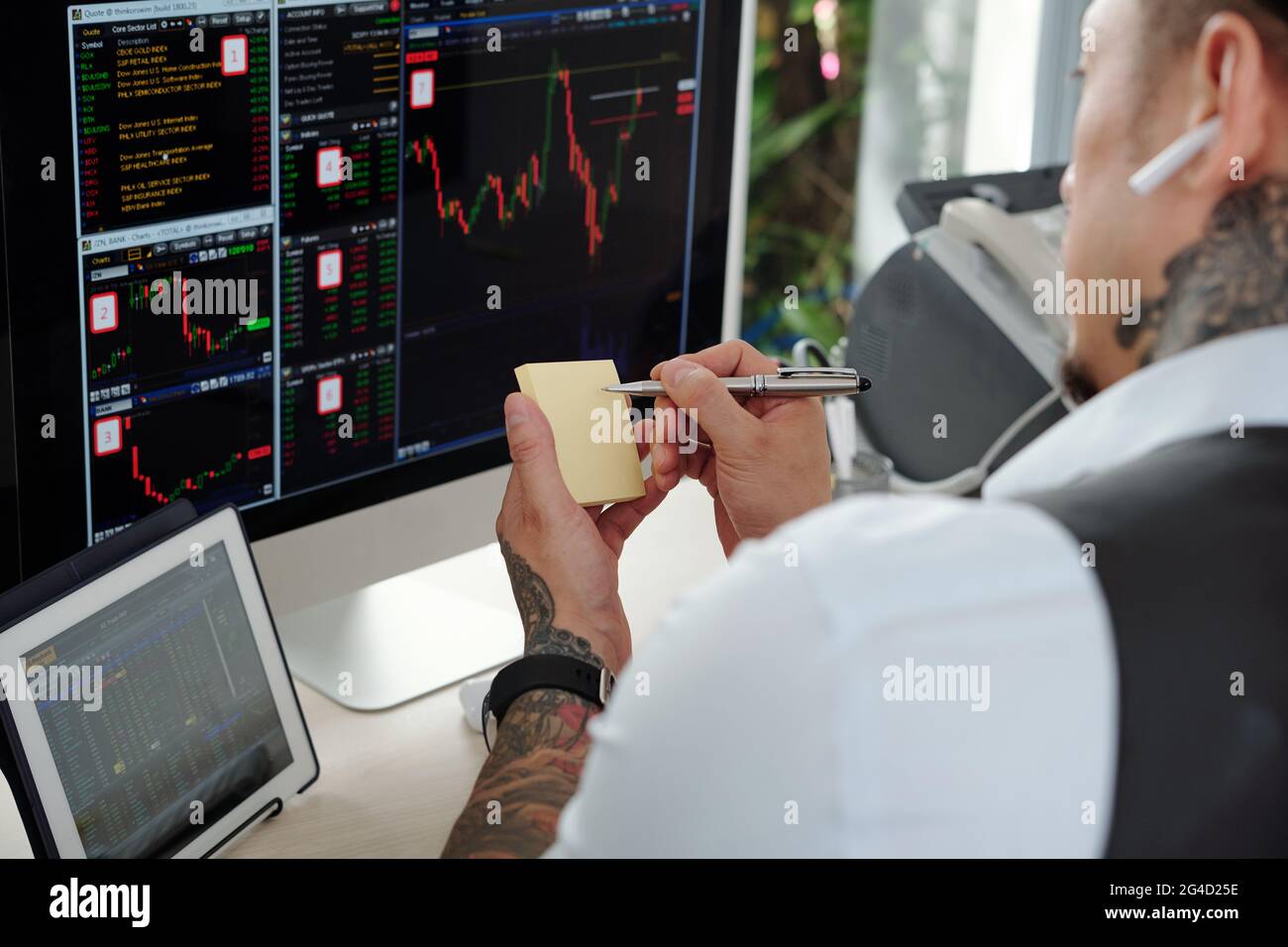 Professional trader analyzing stock market data on computer scren and taking notes on stickers Stock Photo