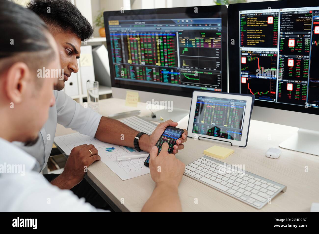 Serious pensive young traders checking cryptocurrency prices online via application on smartphone Stock Photo