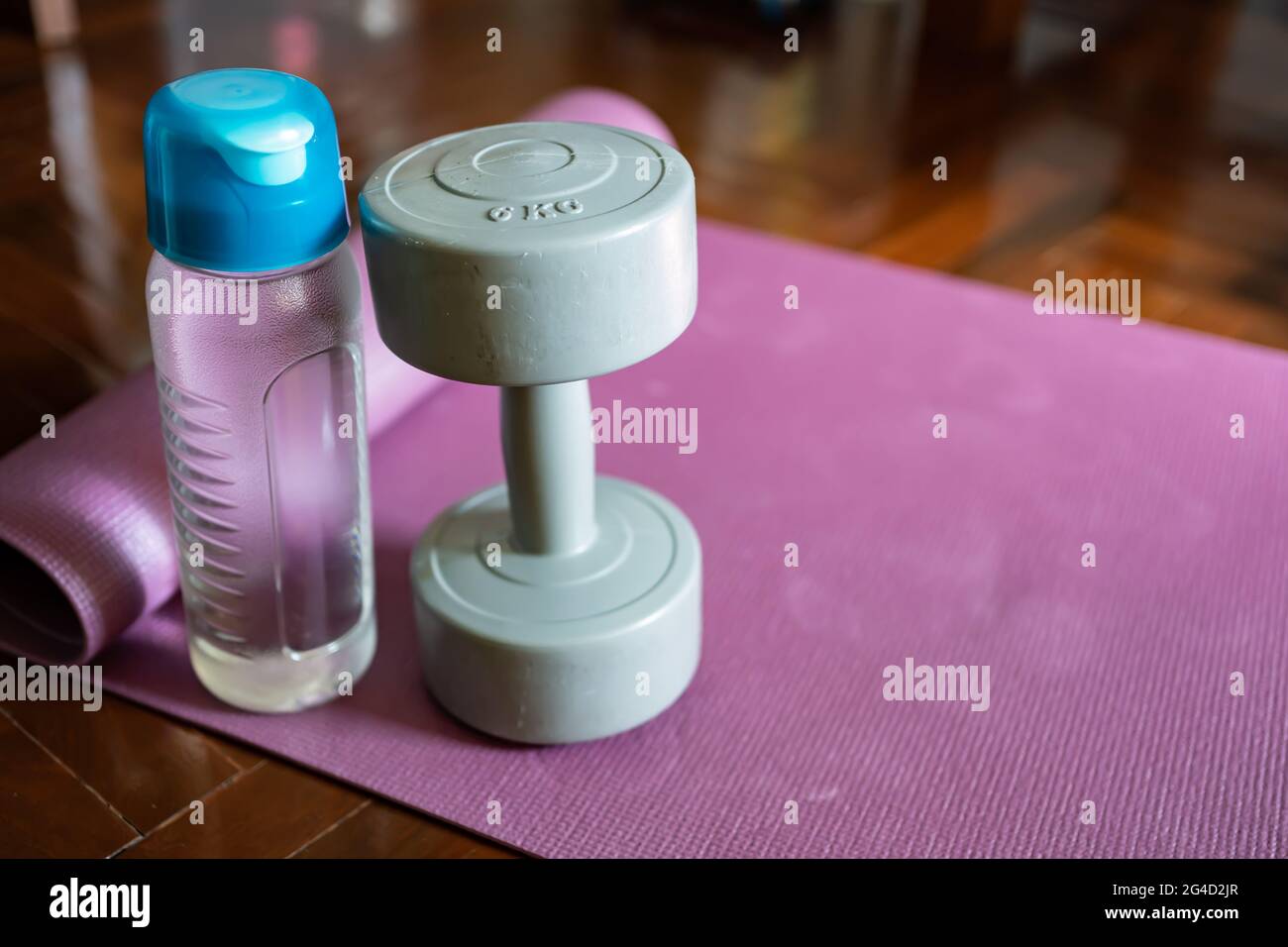 Dumbbell and water bottle on yoga mat Stock Photo
