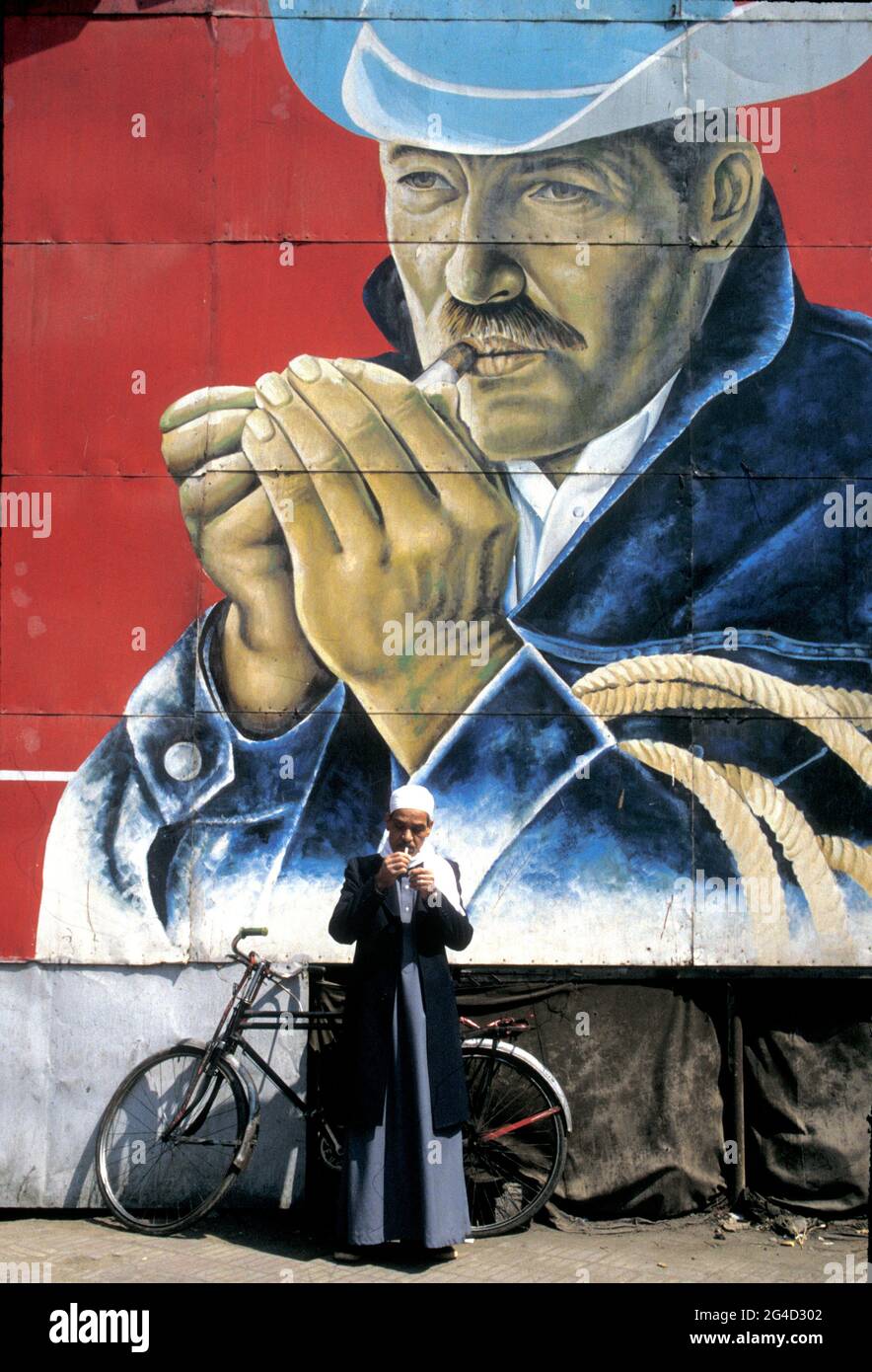 Man lighting cigarette beneath the Marlboro poster in Cairo, Egypt Stock Photo