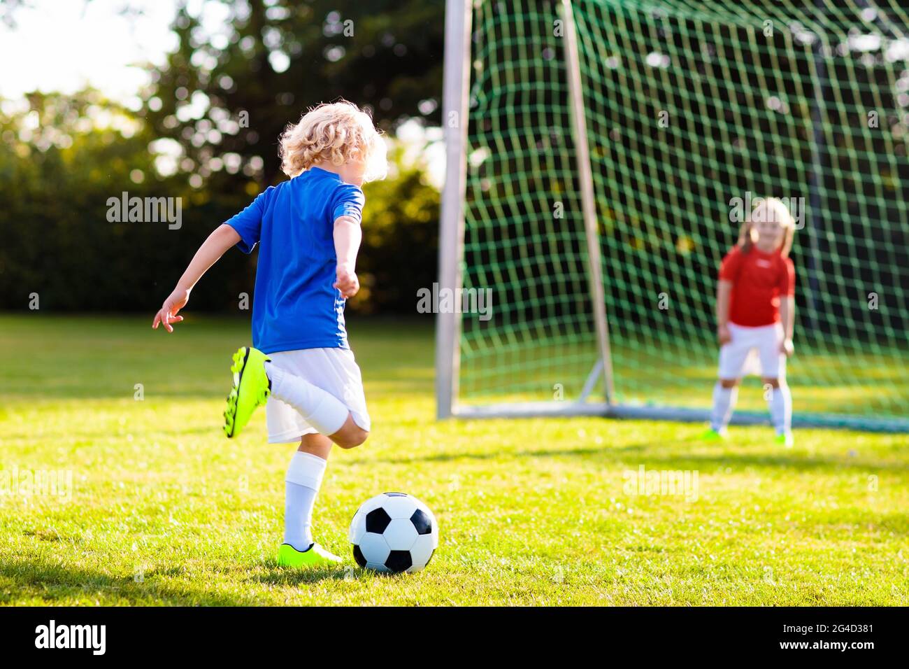 Kids play football on outdoor field. Children score a goal during