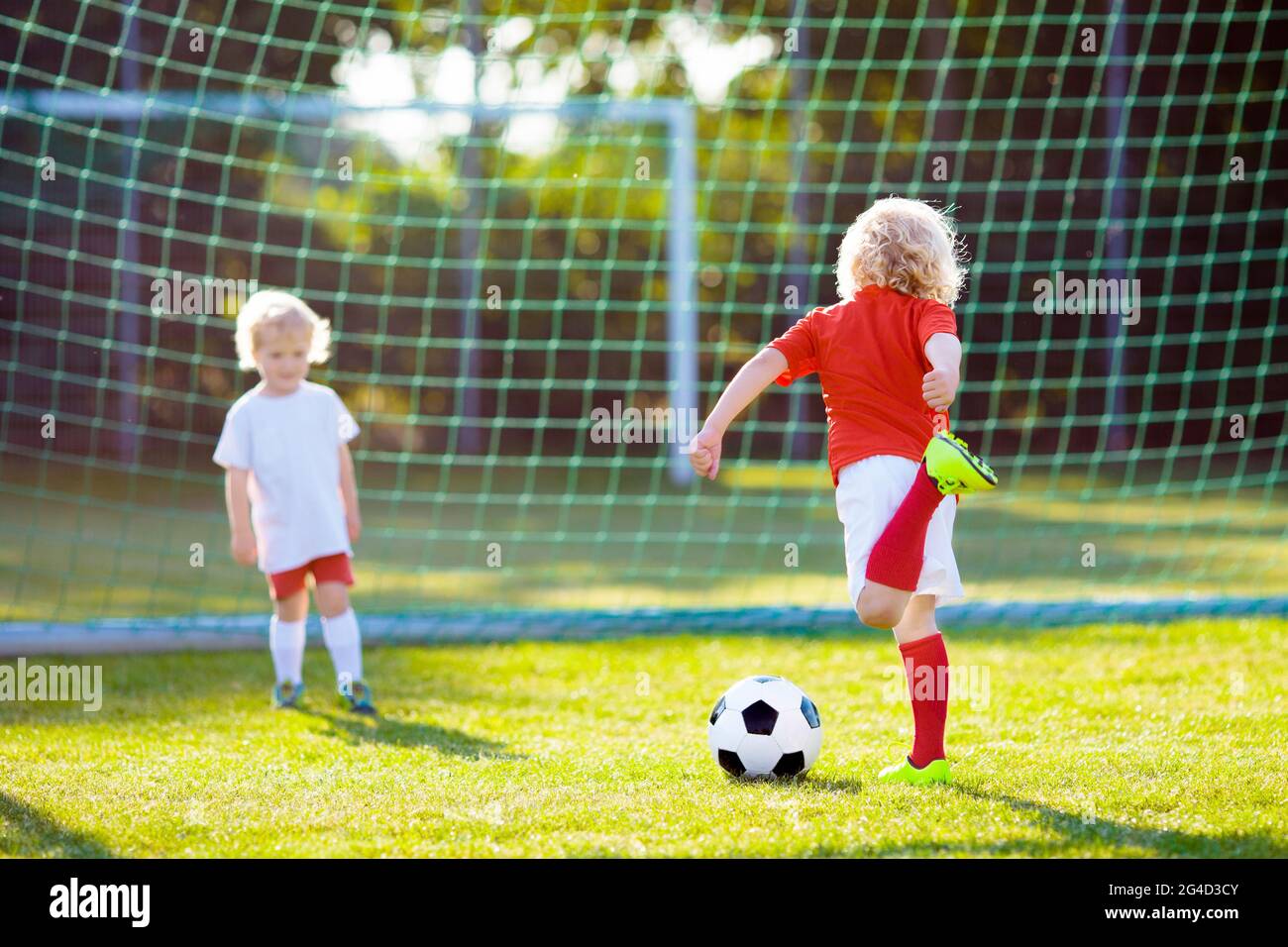 Kids play football on outdoor field. Children score a goal at soccer ...