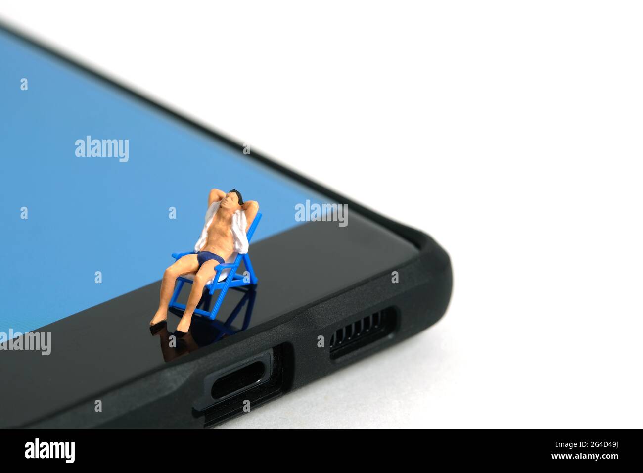 Miniature people toy figure photography. Virtual travel concept, Men relaxing seat at chair above smartphone, isolated on white background. Image phot Stock Photo