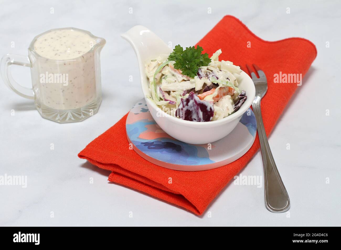 Fresh, organic cole slaw in a handled dish with pitcher of dressing on the side.  Macro view. Stock Photo