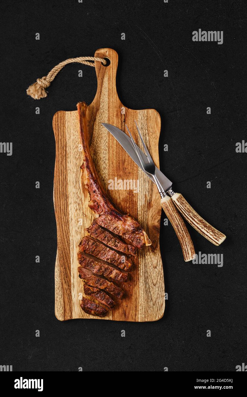 Tomahawk steak cut on slices on wooden board Stock Photo