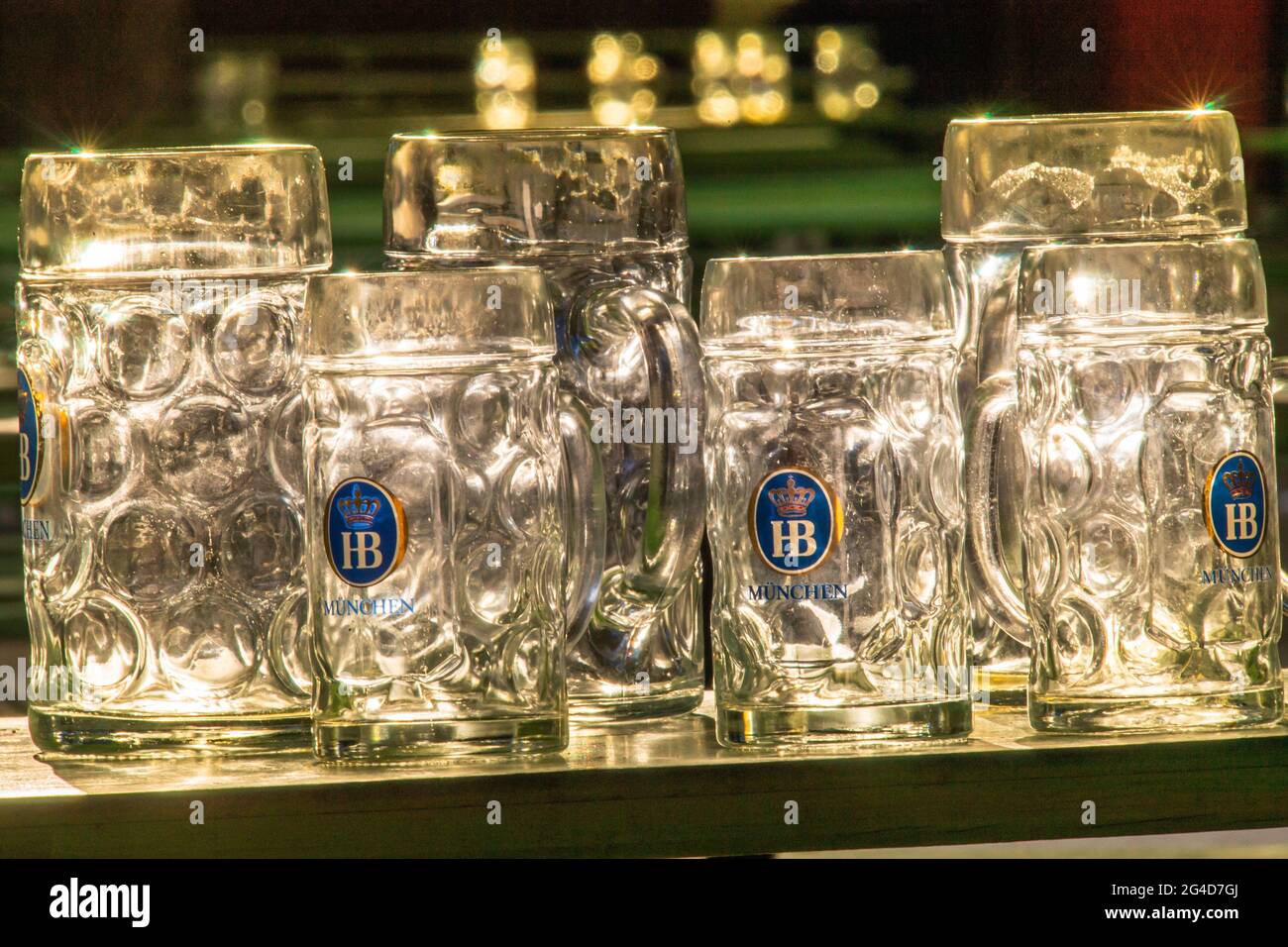 Munich, Germany. 21st June, 2021. Several beer mugs with the Hofbräu München logo stand on a table in the Biergaren at the Chinese Tower in the English Garden in the sun that shines through the glasses. Credit: Peter Kneffel/dpa/Alamy Live News Stock Photo