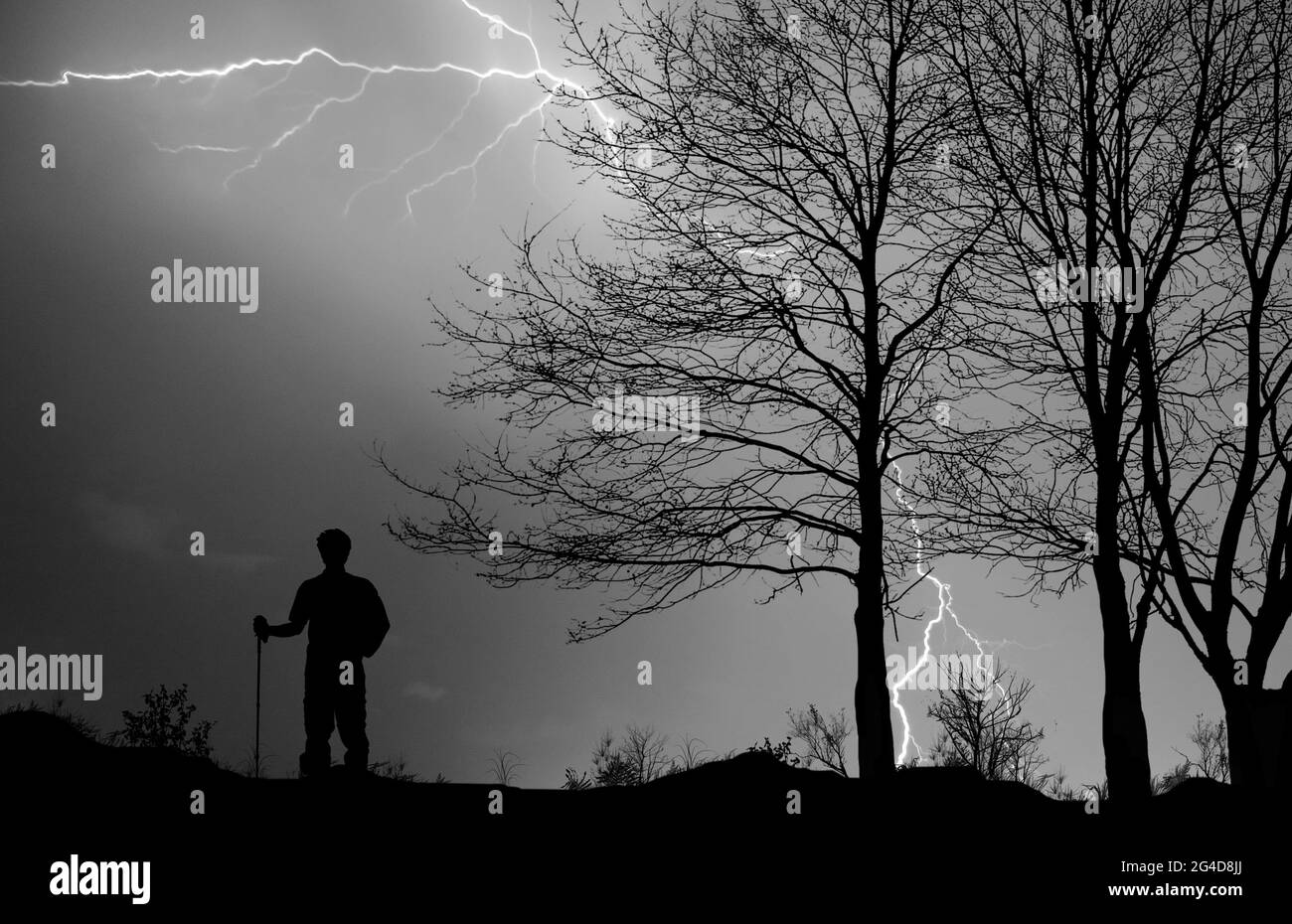 Dramatic view of the silhouette of a hiker in a thunderstorm with lightning flashing Stock Photo