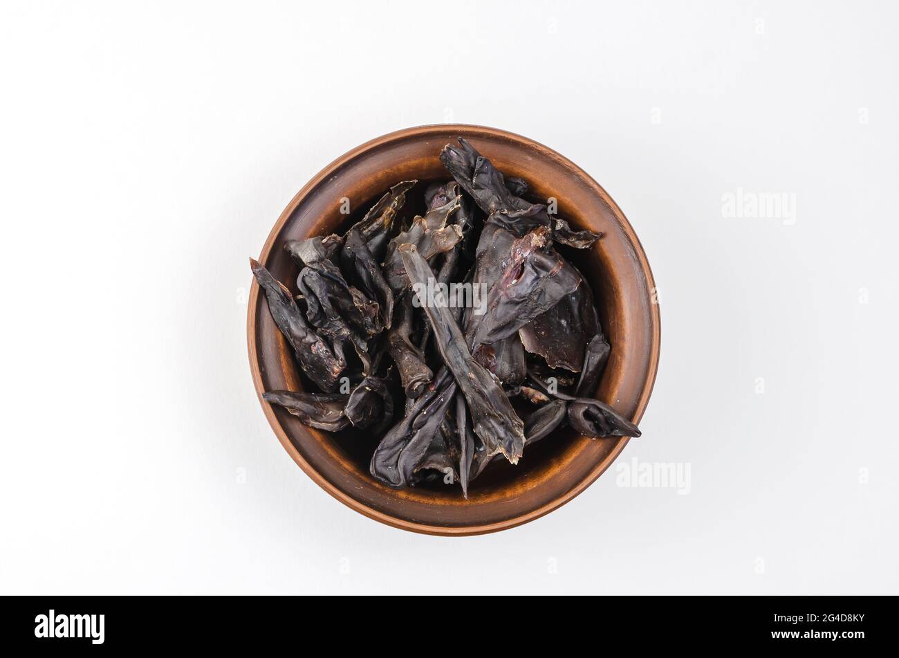 Dried dog treats in a brown clay bowl on a white background. Thin slices of dehydrated beef kidneys. Training treats for pets. Top view Stock Photo