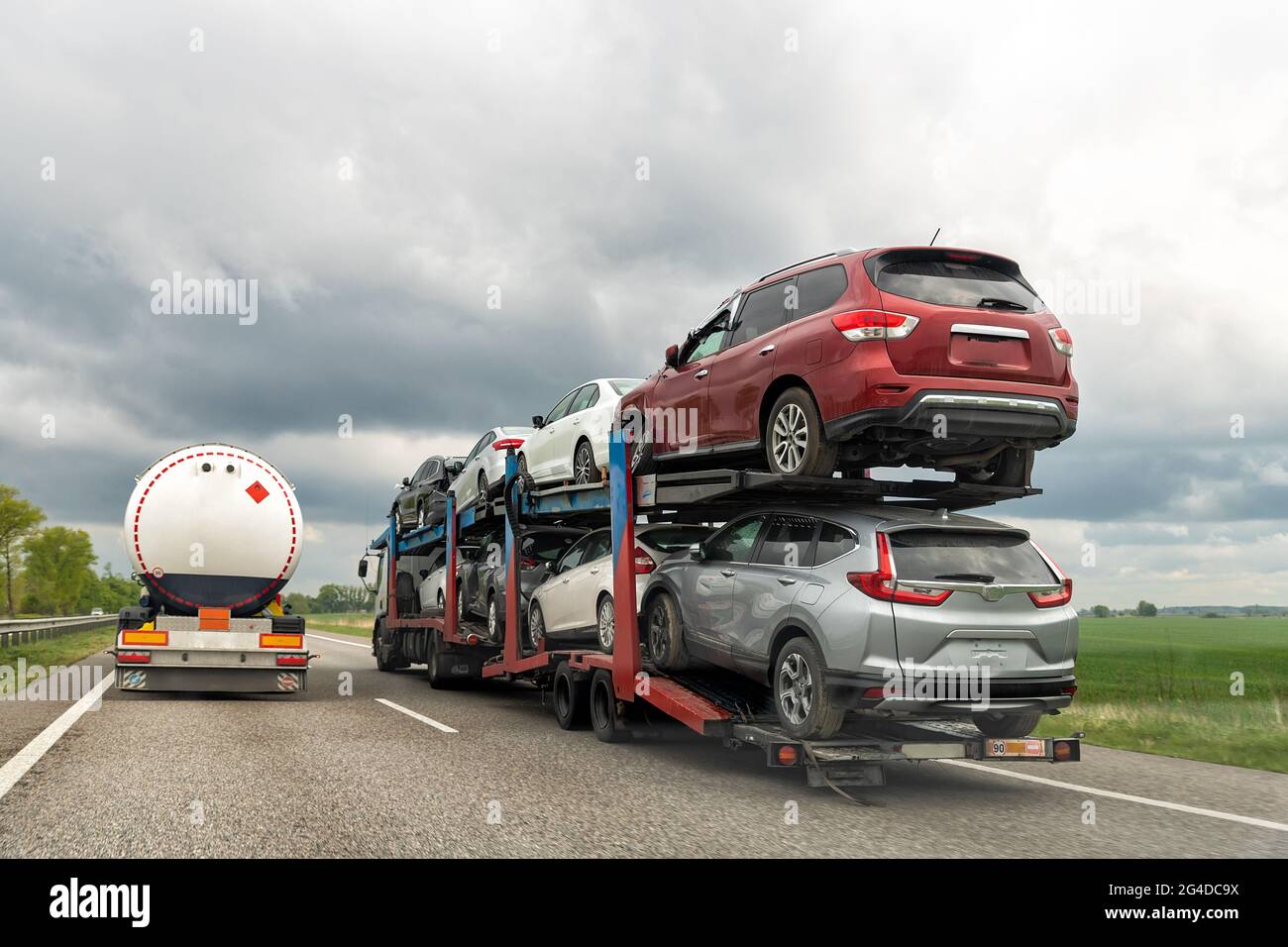 Tow truck car carrier semi trailer on highway carrying batch of damaged cars sold on insurance car auctions for repair and recovery. Vehicles shipment Stock Photo