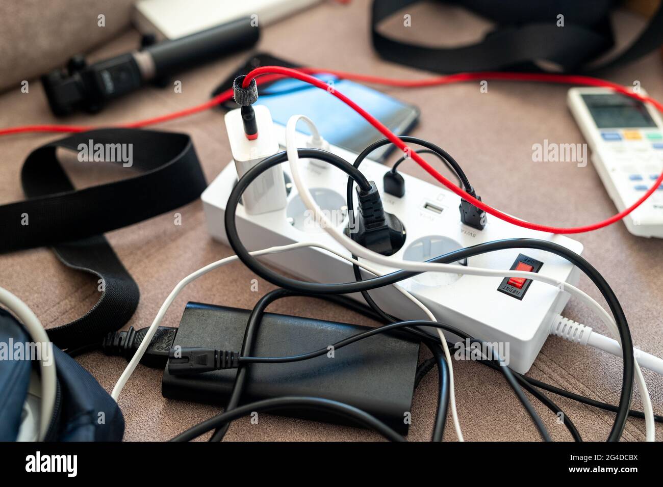 Overloaded power socket plug extendion at home. Tangled cords of home appliances and chargins gadgets mess Stock Photo