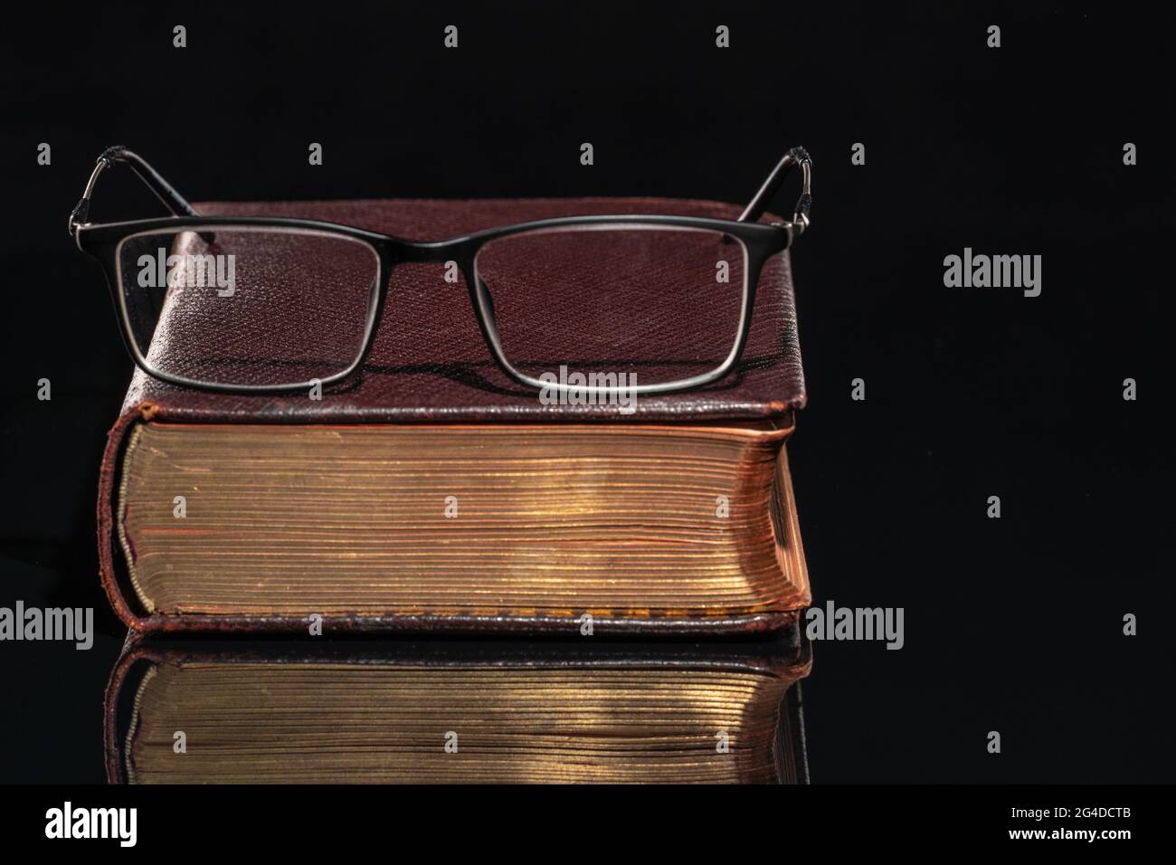 An old book with glasses lying on it Stock Photo