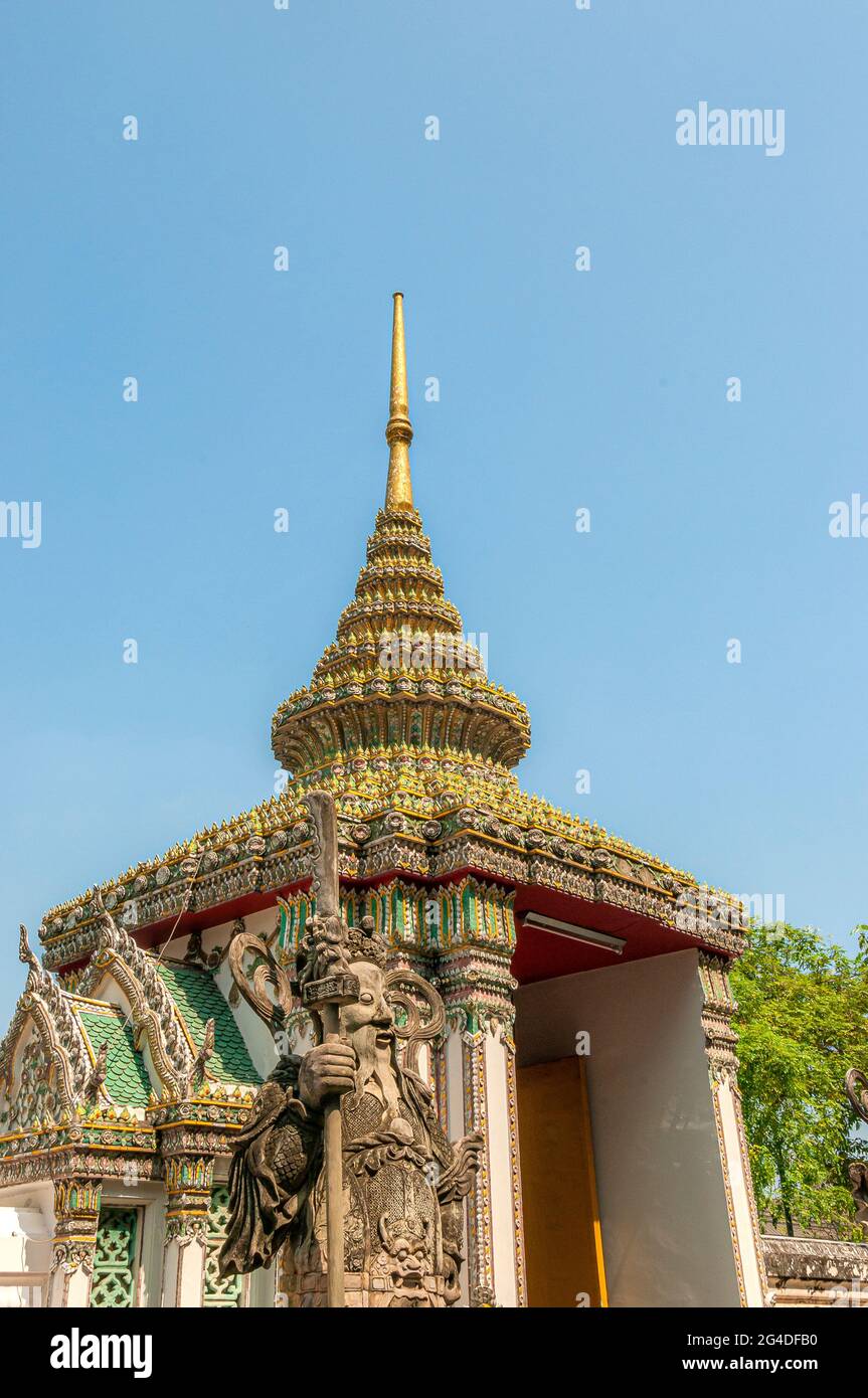 A spectacular highly decorated gateway building and guarded by Guardian statue at Wat Pho Wat Po Buddhist temple in Bangkok in Thailand. Stock Photo